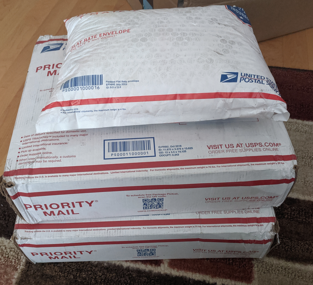 Two medium USPS packages with a third smaller one on top